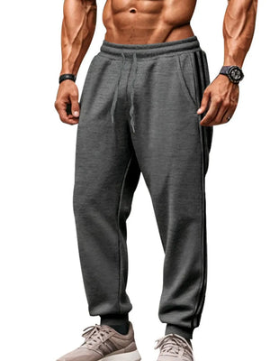 Gray joggers with black athletic stripes on the side, drawstring waist, and cuffed ankles.