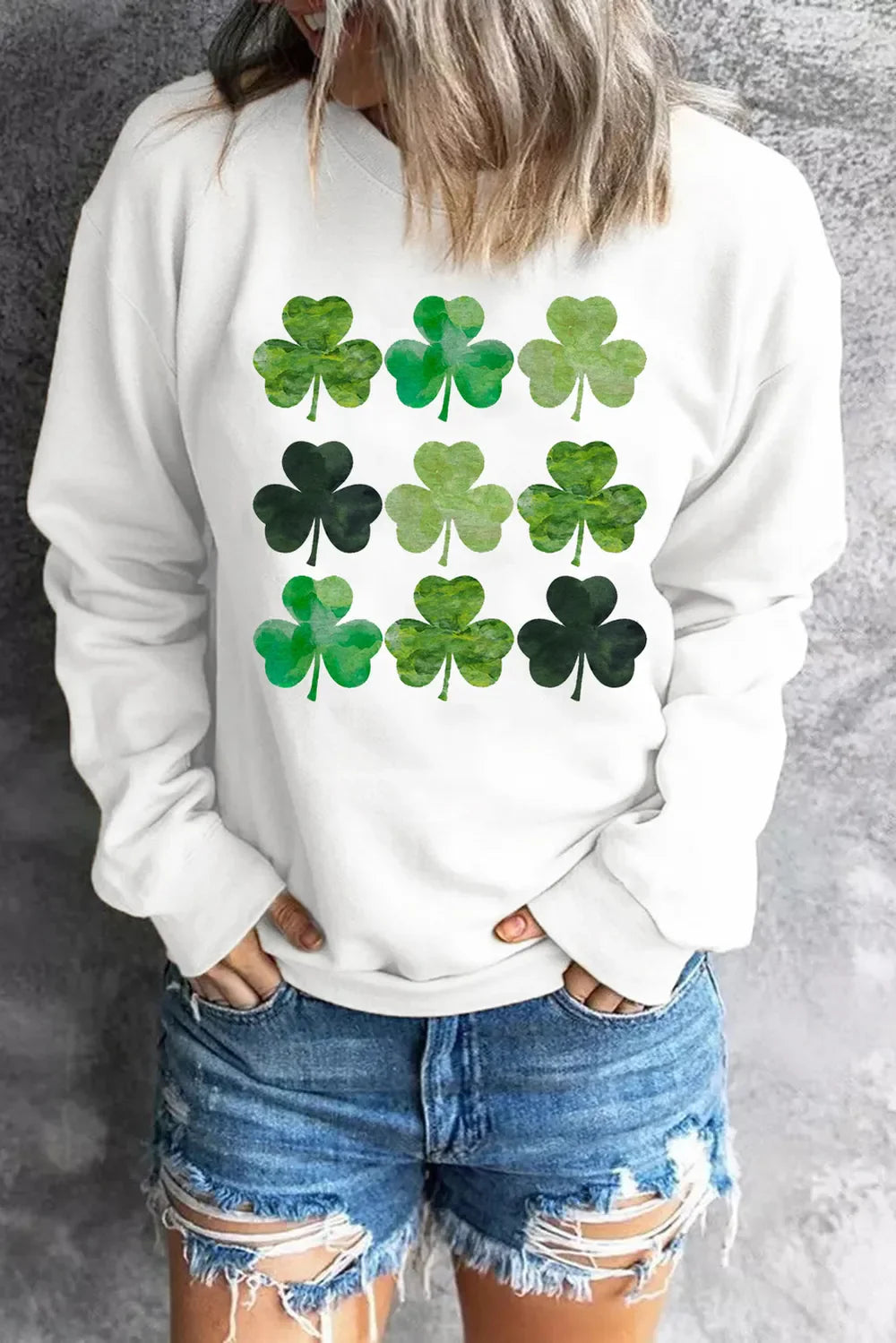 White crewneck sweatshirt with a grid of green clover prints.