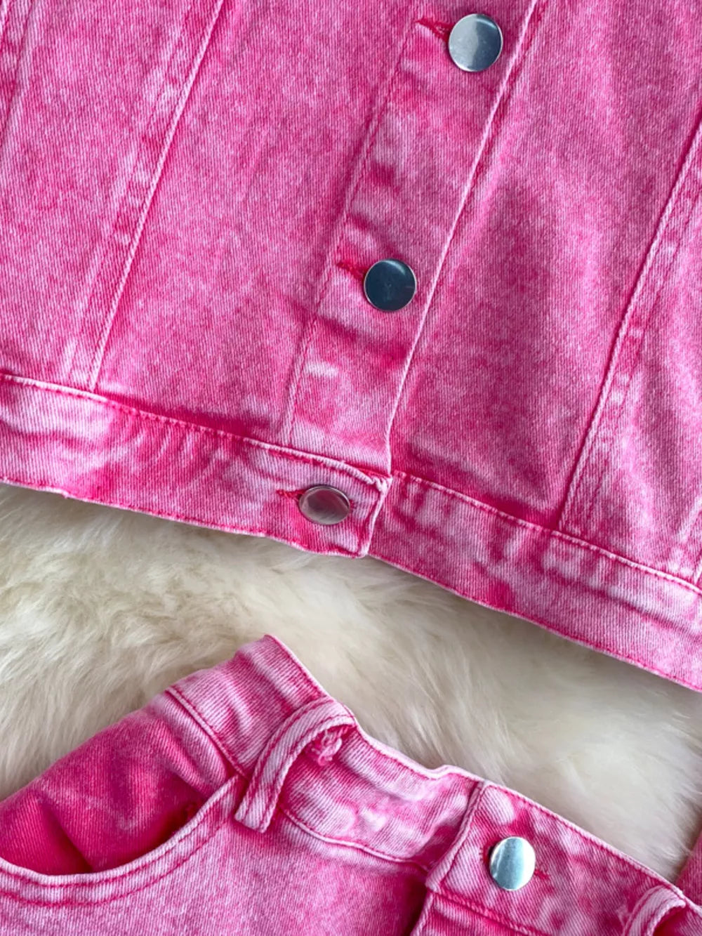Pink acid wash denim jacket and skirt set with silver button details.