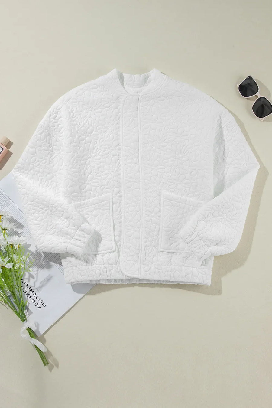 White quilted bomber jacket with floral pattern and two front pockets.