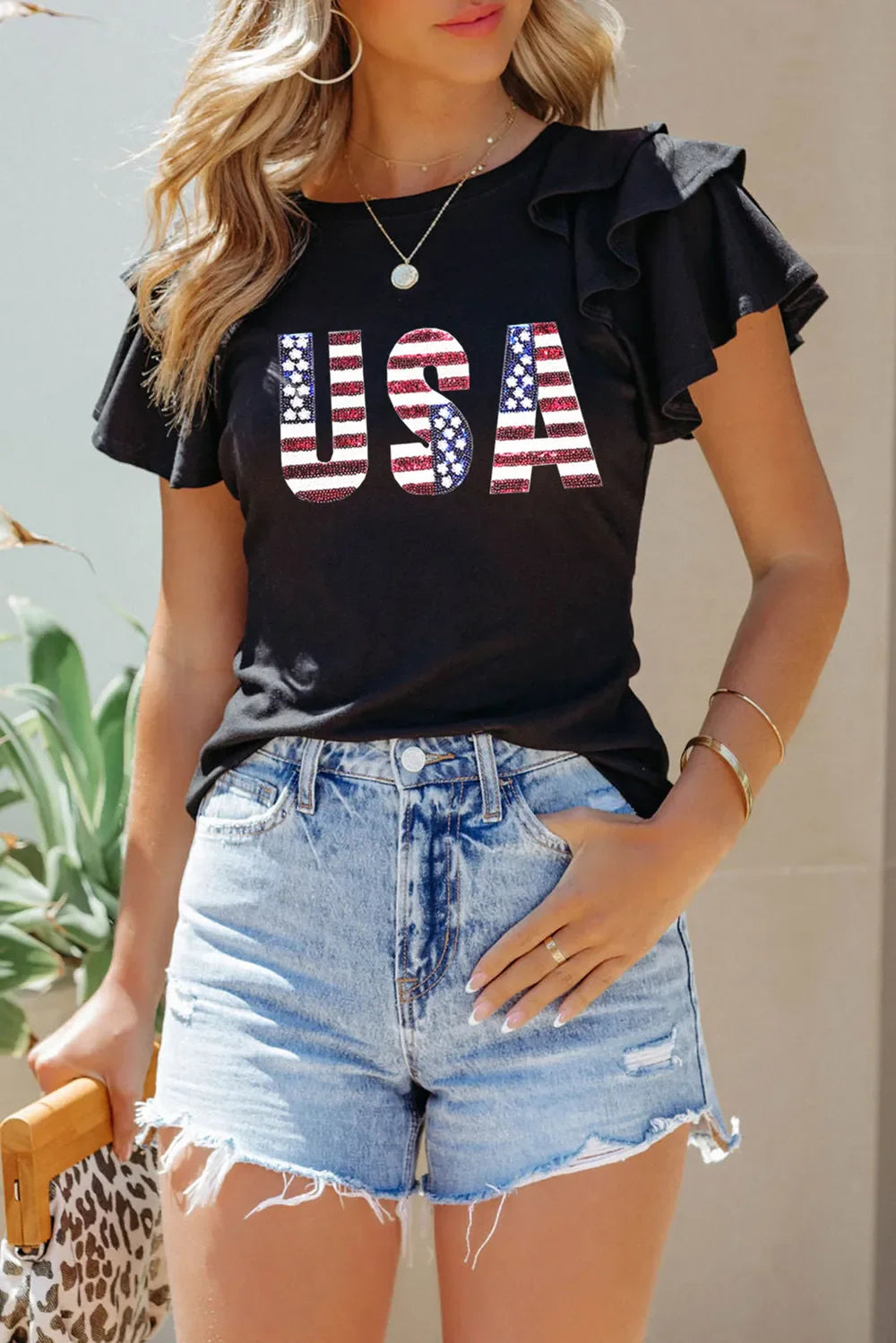 Black t-shirt with USA flag graphic and ruffle sleeves.