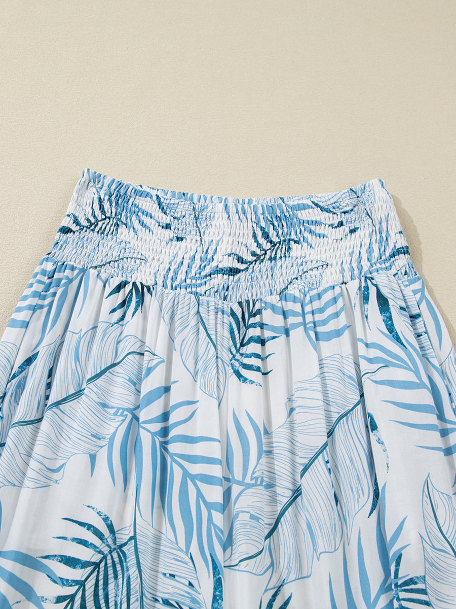 Tropical leaf print wide leg pants with smocked waistband and blue and white pattern.