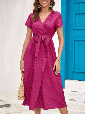 Wrap dress in magenta with red polka dots, short sleeves, V-neck, and tie waist.