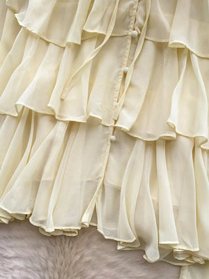 Yellow chiffon blouse with tiered ruffles and button-down detail.