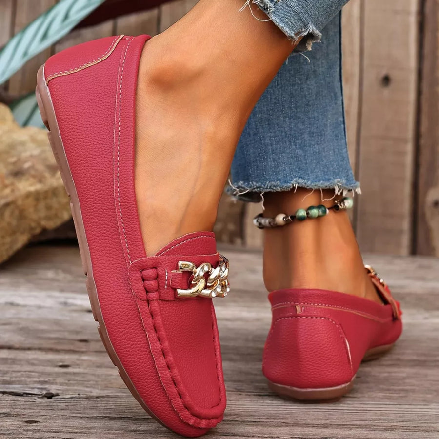 Red round-toe loafers with gold chain detail and stitched accents.