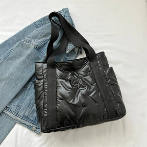 Black padded nylon tote bag with exterior pockets and quilted stitching detail.
