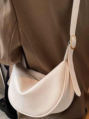 Beige white crescent pu leather crossbody bag with adjustable strap and gold buckle.