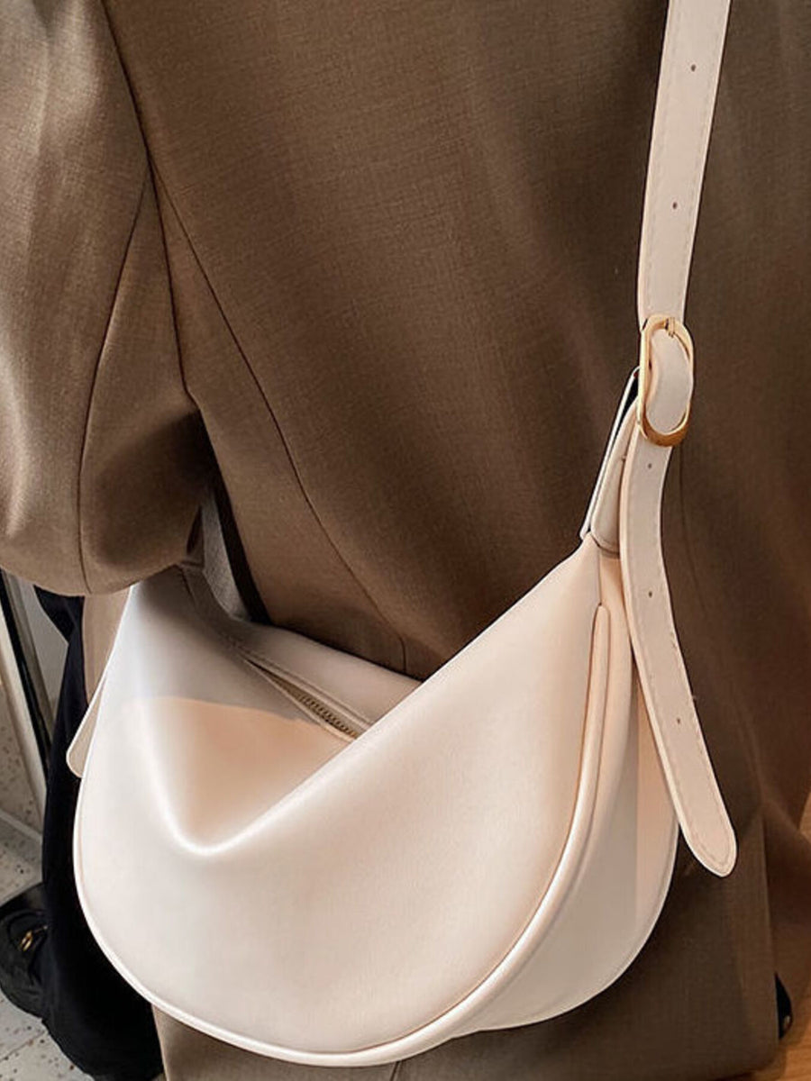 Beige white crescent pu leather crossbody bag with adjustable strap and gold buckle.