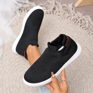 Black knit slip-on sneakers with white soles and red accent trim.