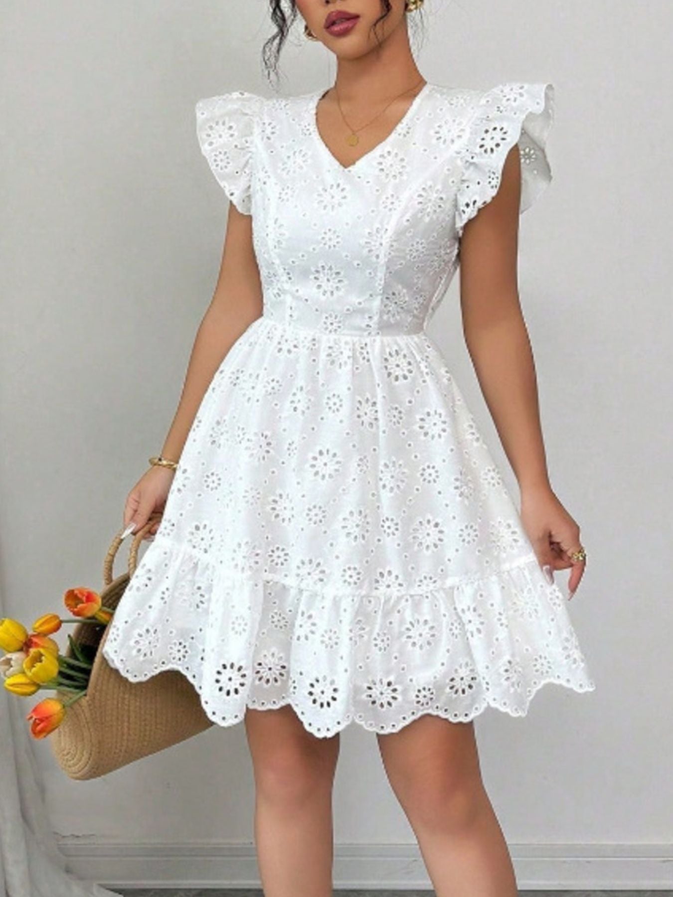 White eyelet mini dress with ruffle sleeves and v-neck, tiered hem.