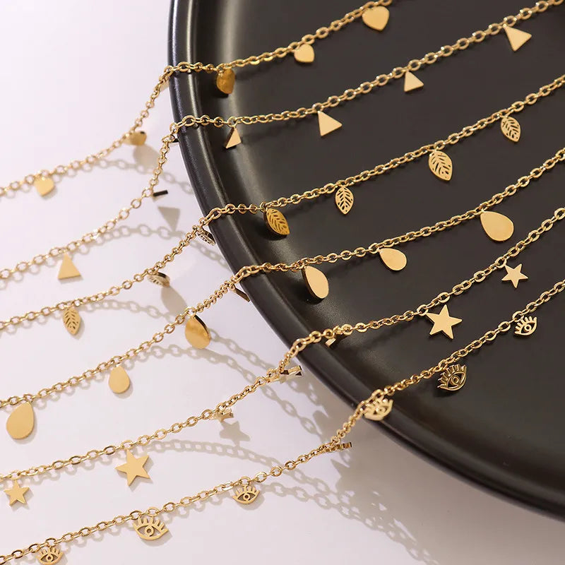 Gold dangling charm chain necklace with hearts, stars, leaves, teardrops, and eyes.