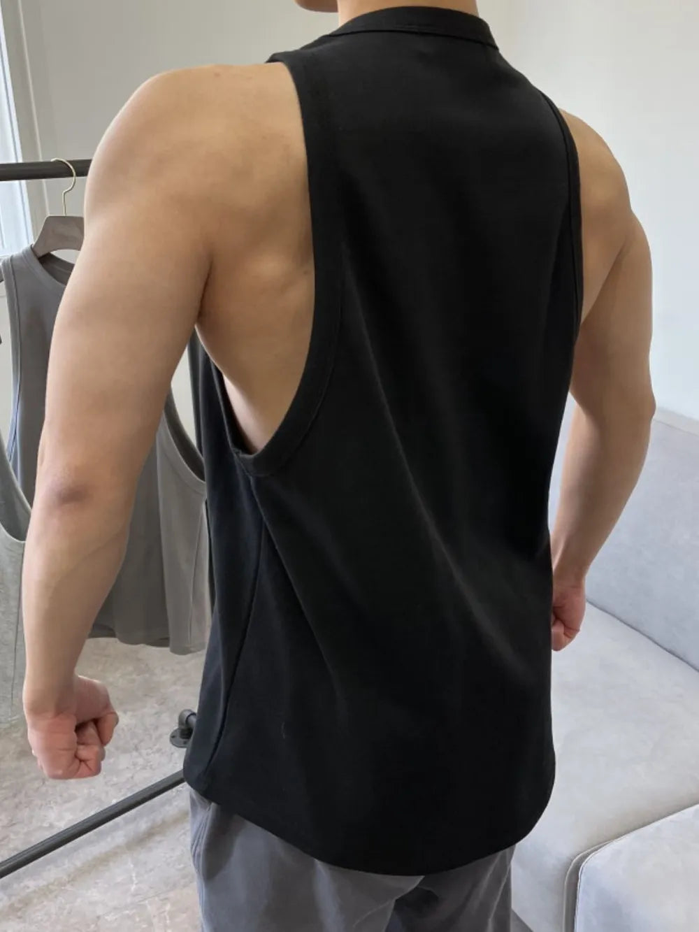 Black sculpted muscle tank top with open sides and a collar detail.