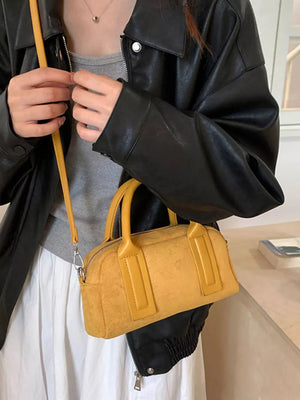 Chic yellow suede crossbody bag with handles and a zip closure.