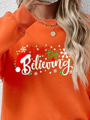 Orange long sleeve sweater with "Don't Stop Believing" graphic and Santa hat detail