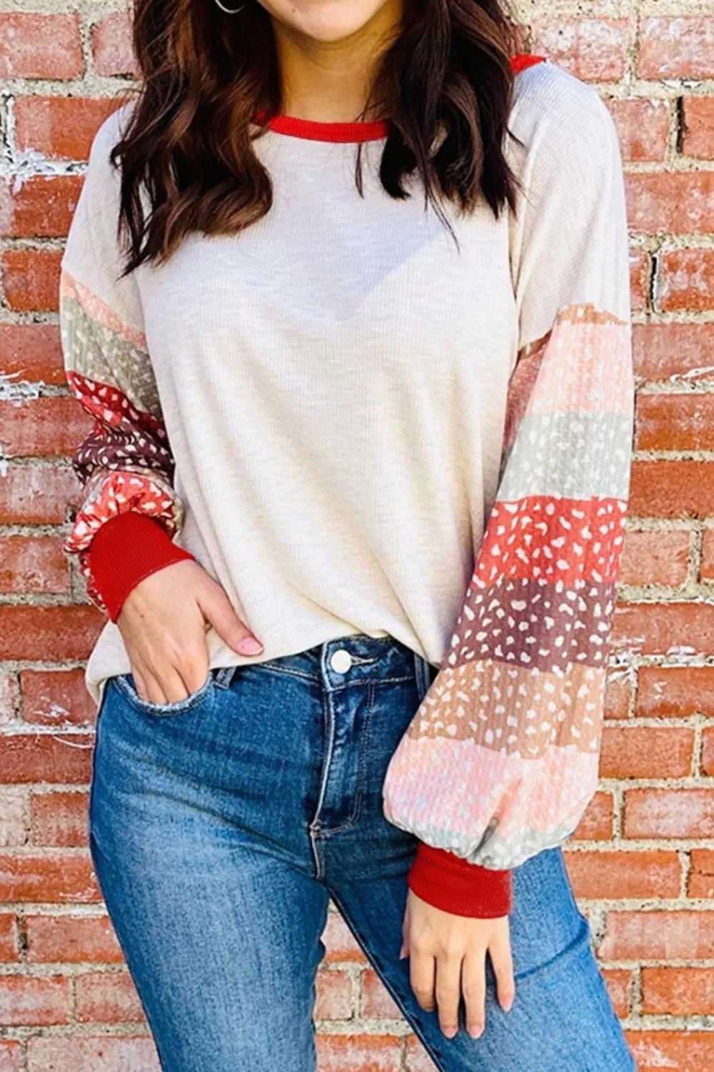 Cream waffle knit top with multicolor striped puff sleeves and red cuffs.
