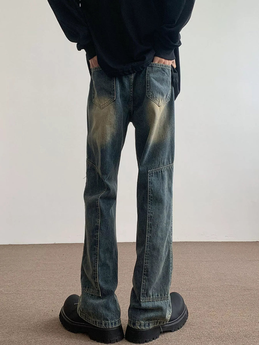 Men's blue vintage wash flare jeans with distressed detailing and paneling.