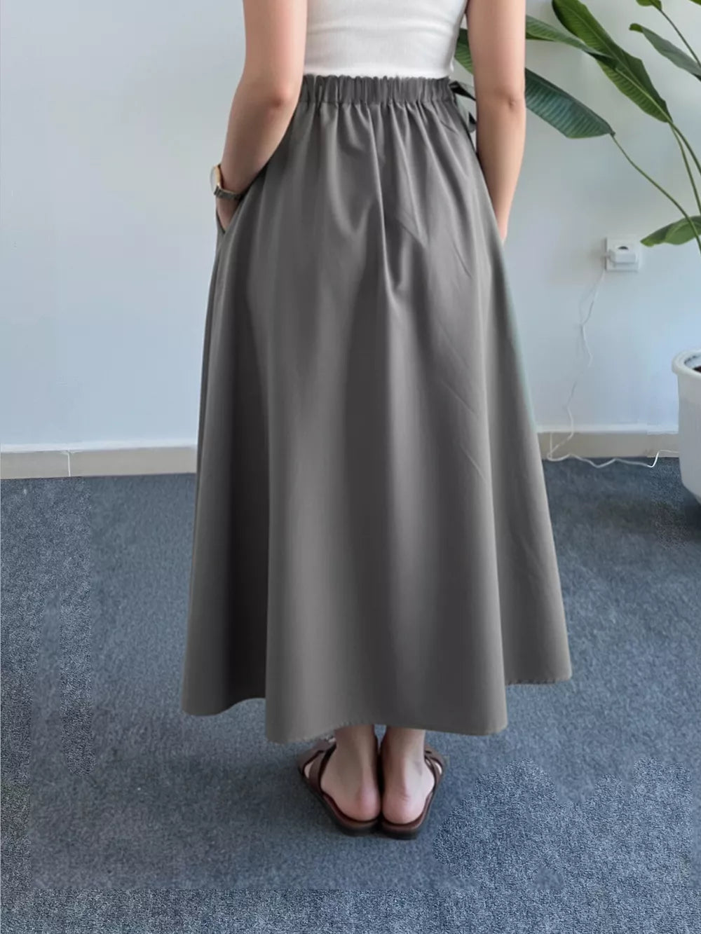 Grey A-line midi skirt with elastic waist and pockets, shown from the back.