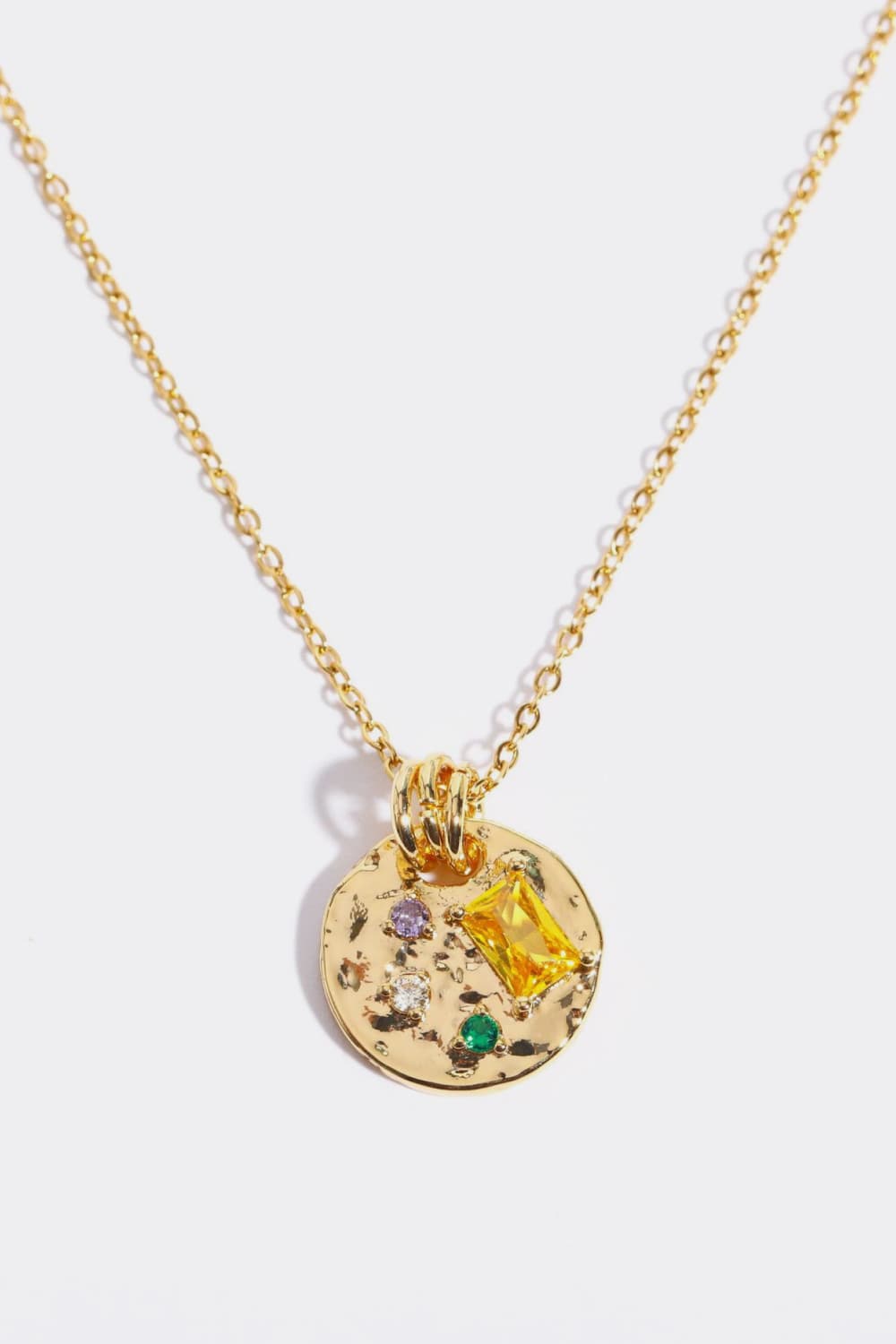 Gold textured disc pendant necklace with colorful gemstone accents