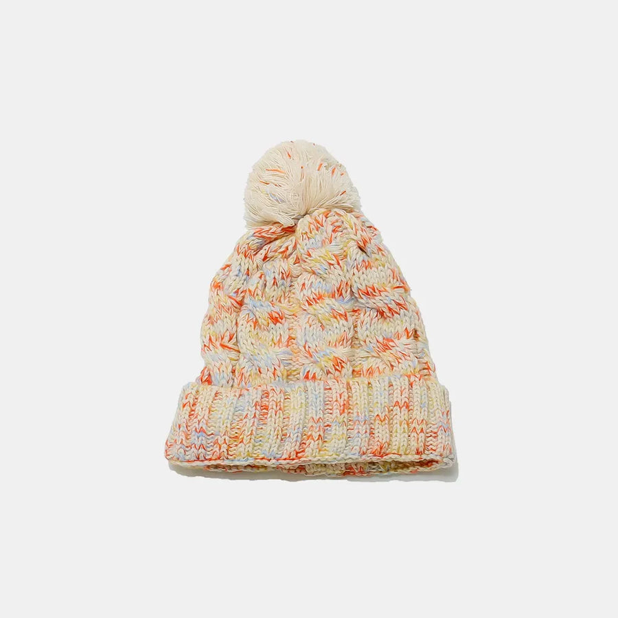 Textured knit beanie with pom in multi-color yarn and cable knit pattern.