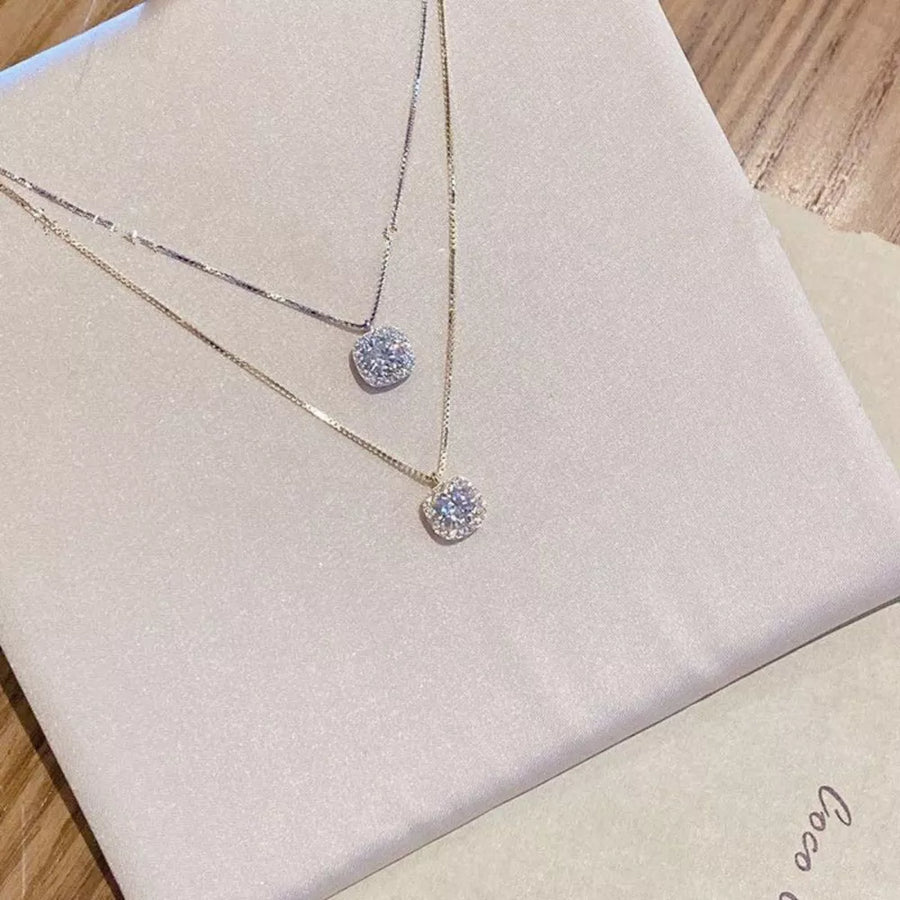 Gold and silver zircon pendant necklaces with box chains on display.