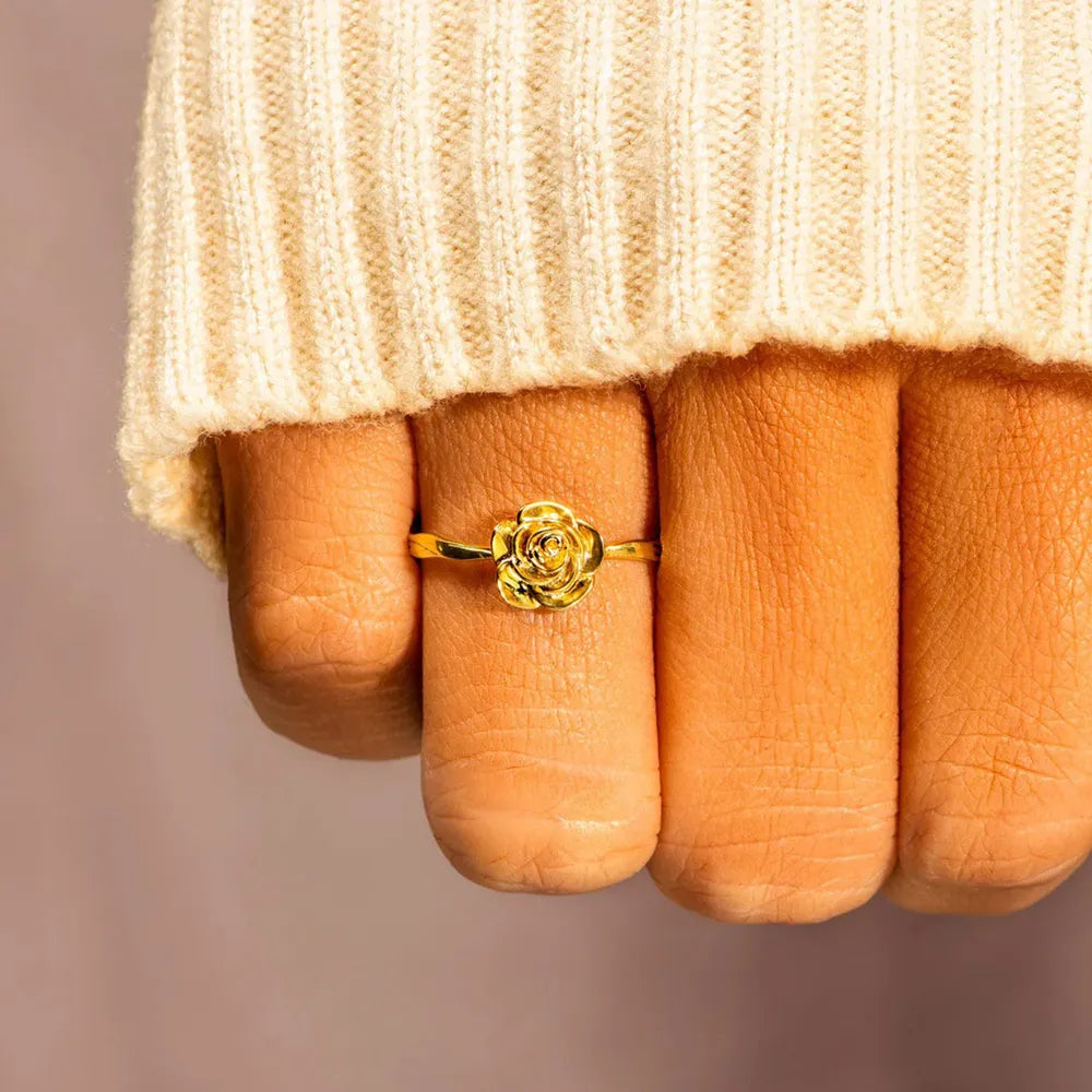 18K gold ring with a sculpted rosebud design, worn on a finger.