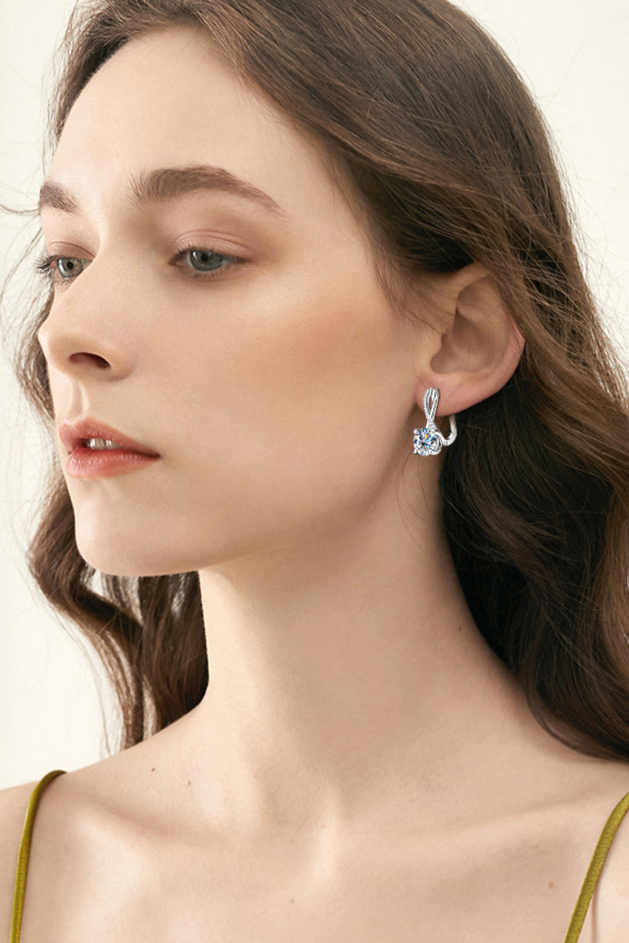 Silver crossover moissanite huggie earrings with a twisted detail and a round stone.