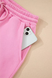 Pink cotton sweat shorts with drawstring waist and phone in pocket.