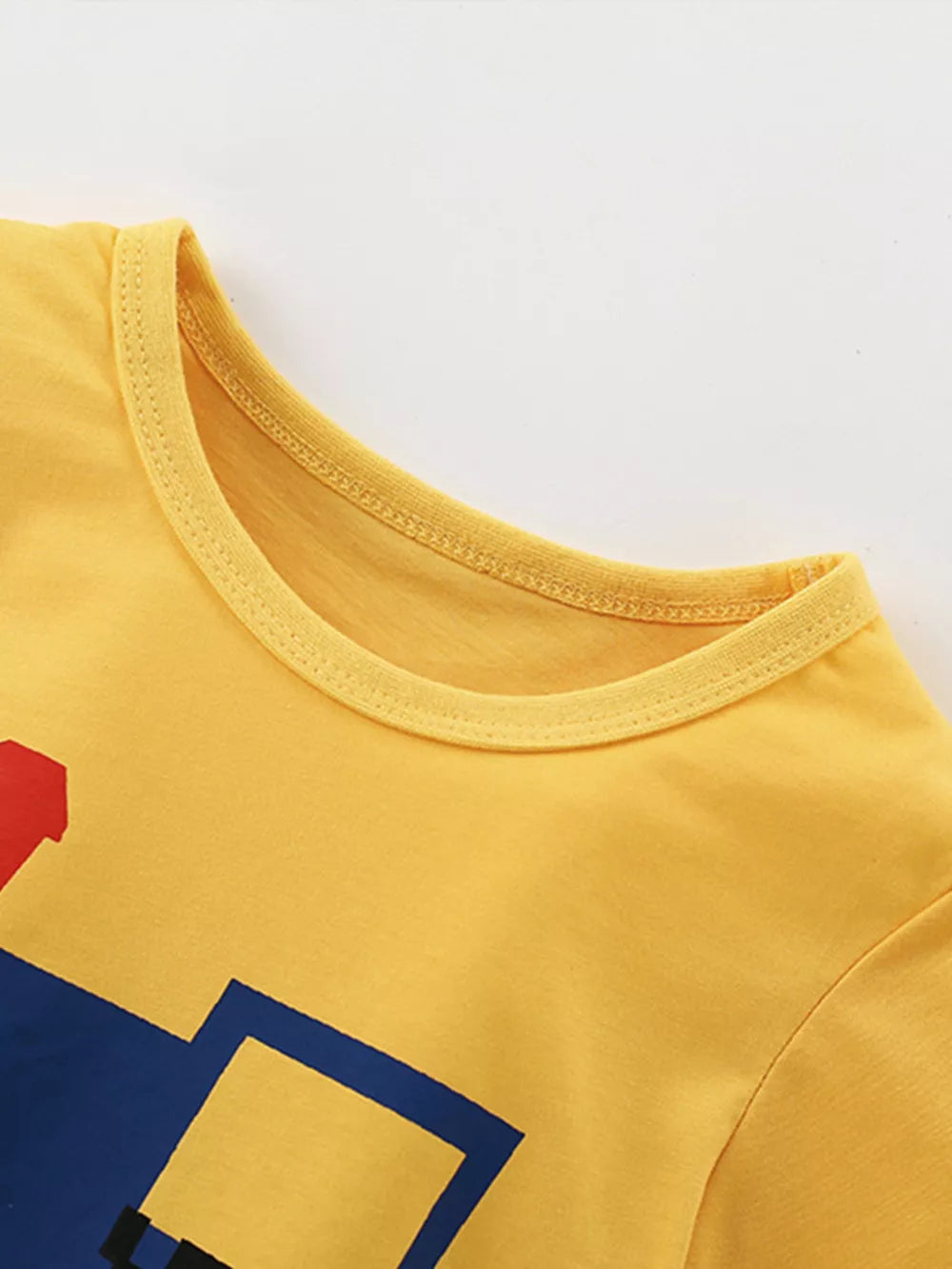 Yellow cotton t-shirt with cartoon train graphic and checkered accents for kids.