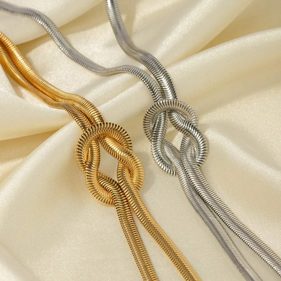 Gold and silver herringbone knot necklaces on satin fabric