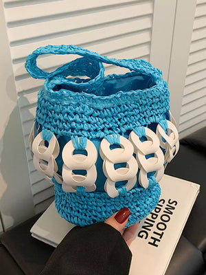 Blue woven straw bucket tote with white ring embellishments and braided strap.
