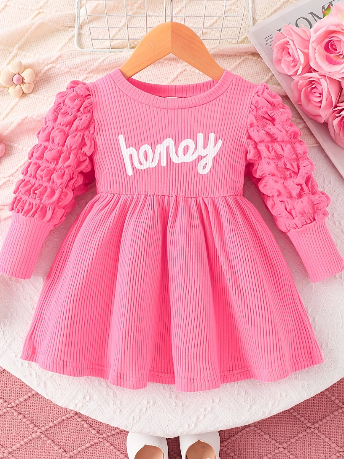 Pink ribbed baby dress with "honey" graphic and textured bubble sleeves