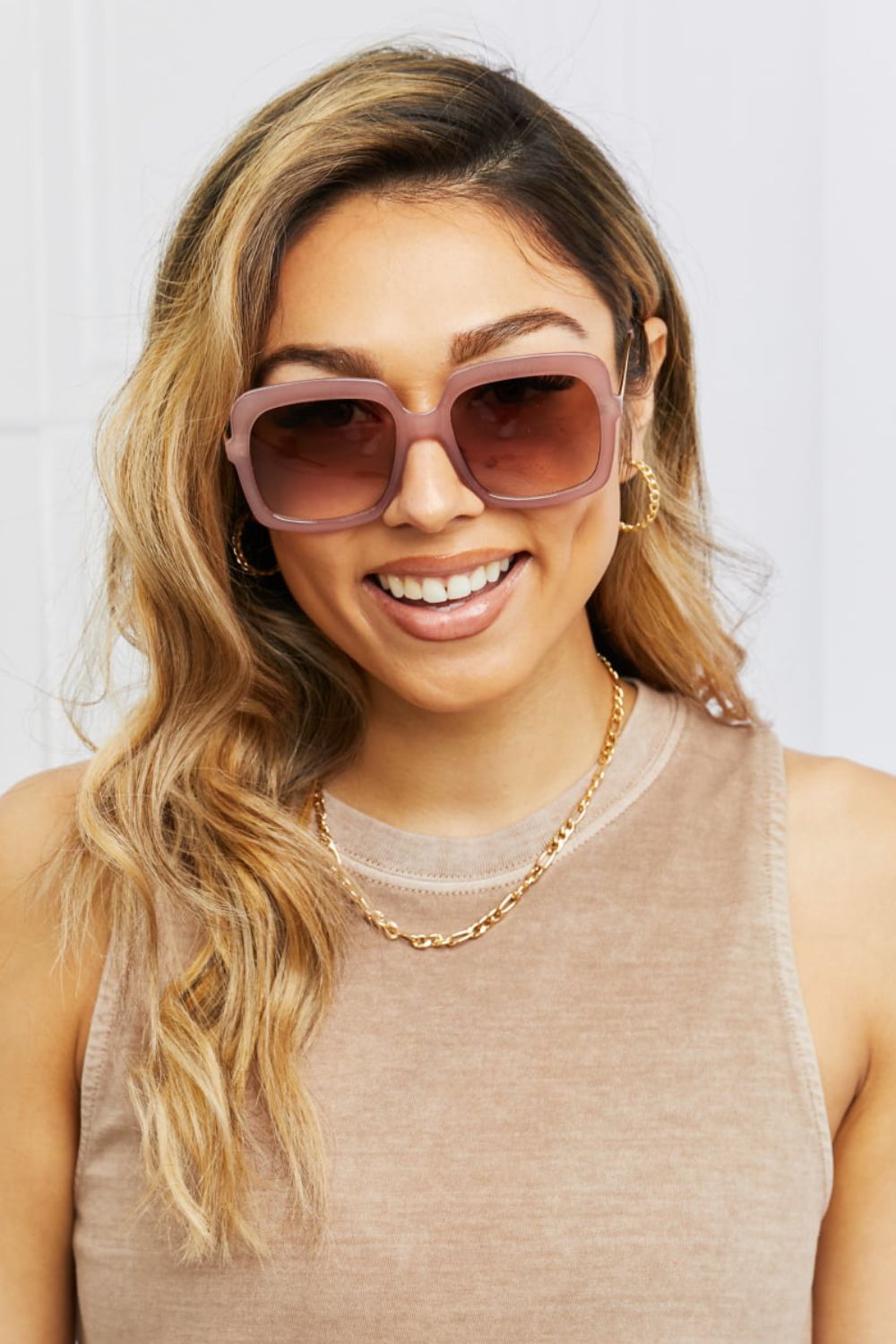 Sculpted square frame sunglasses in khaki with gradient brown lenses, worn by a woman.