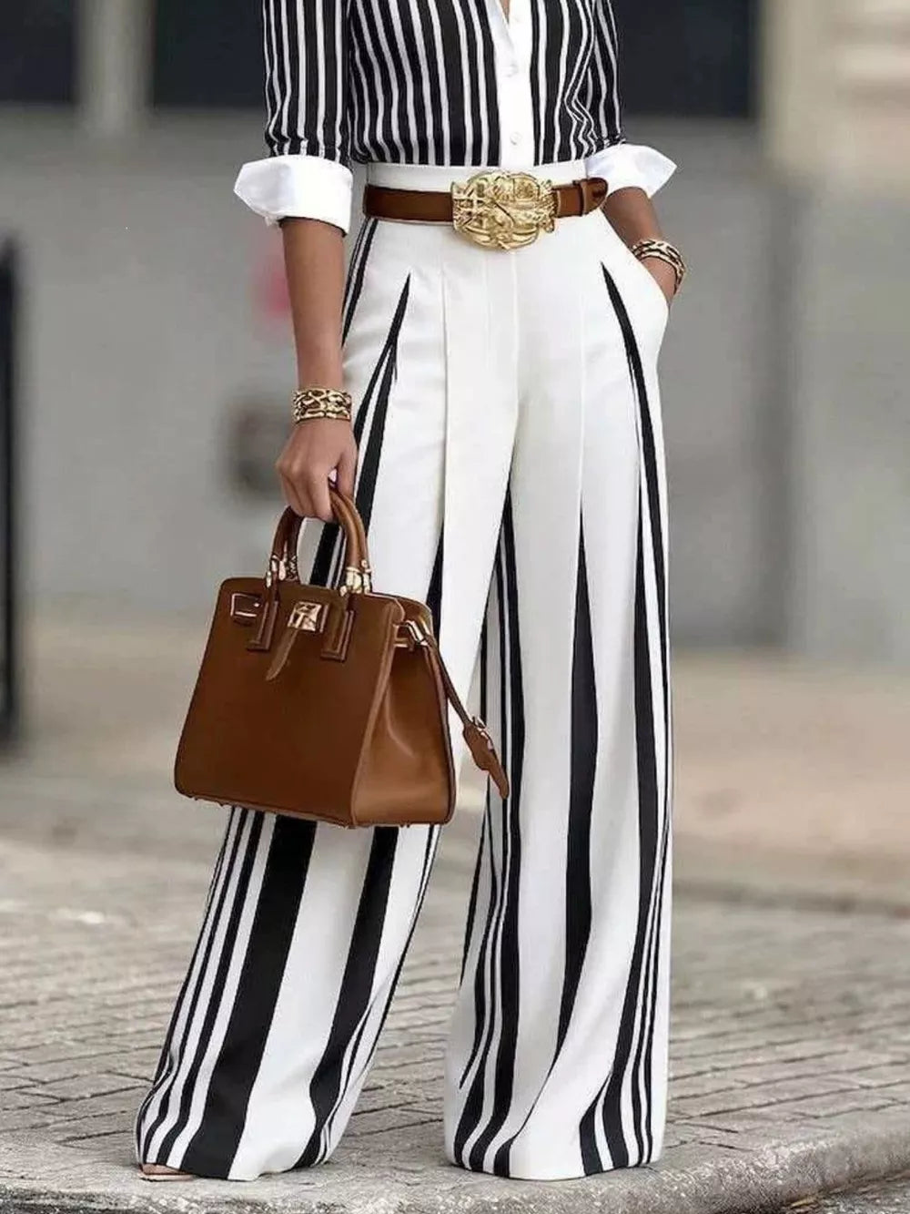 Wide-leg striped pants with pleats, paired with a striped shirt, brown belt, and brown handbag.