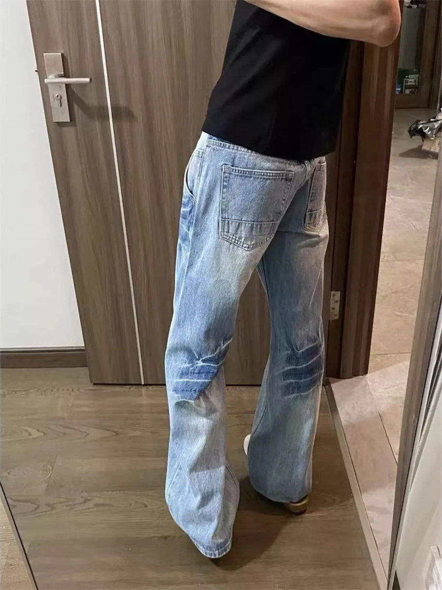 Men's light wash distressed wide leg jeans with patch details.