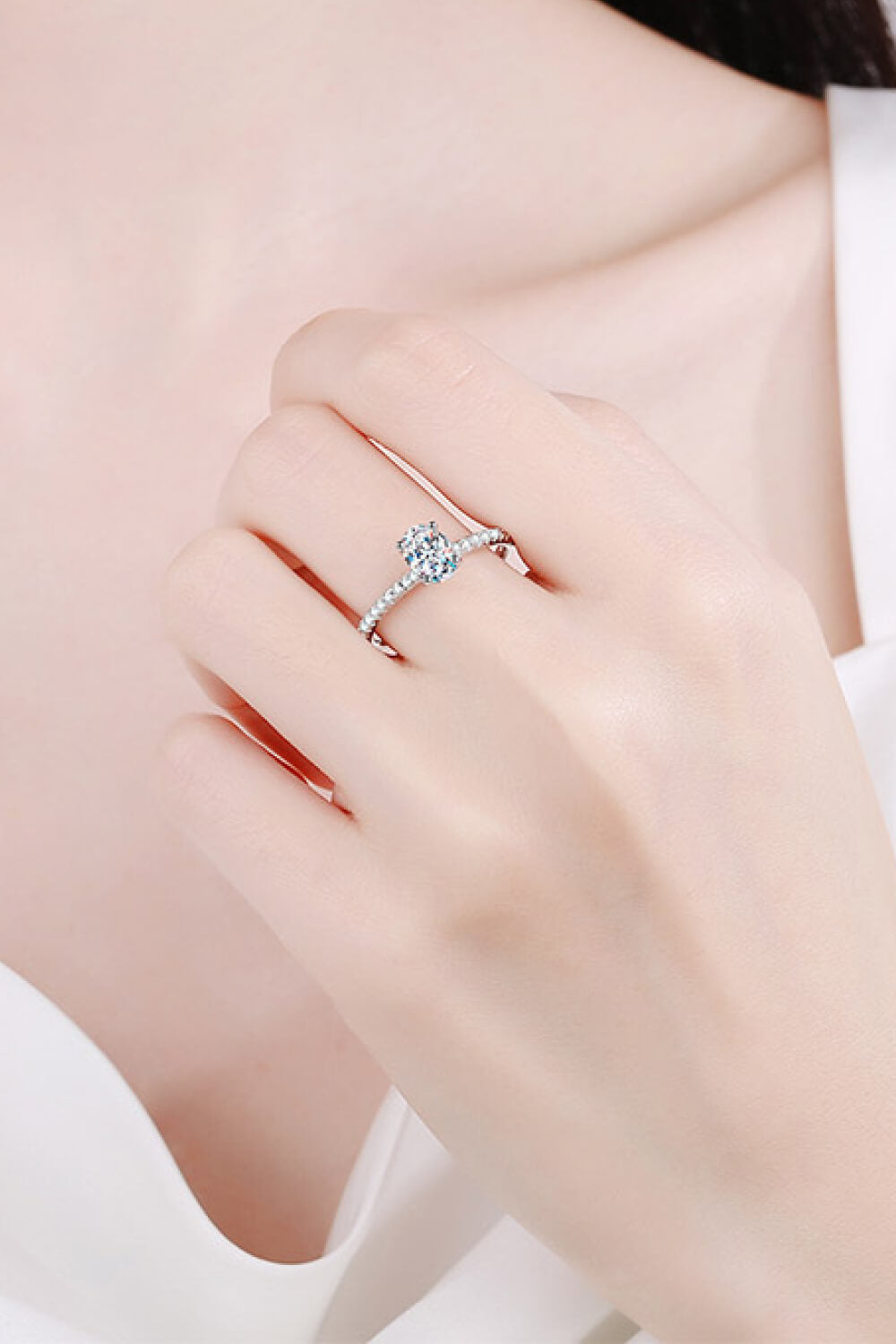 Silver moissanite ring with a solitaire oval stone and pave band.