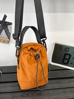 Orange nylon drawstring shoulder bag with black straps and adjustable drawstring closure.