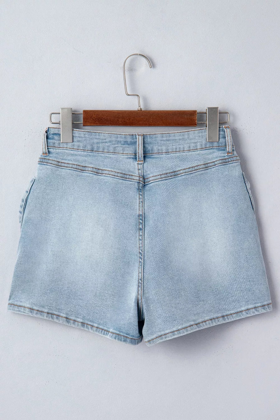 Light wash denim shorts with button fly and bow detail on the side.