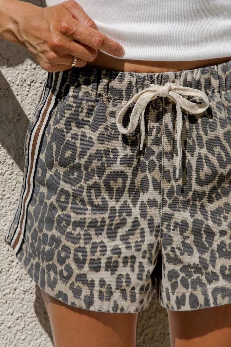 Leopard print denim shorts with drawstring waist and striped side detail.