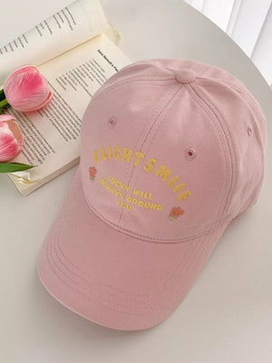 Pink baseball cap with yellow embroidered text and floral details