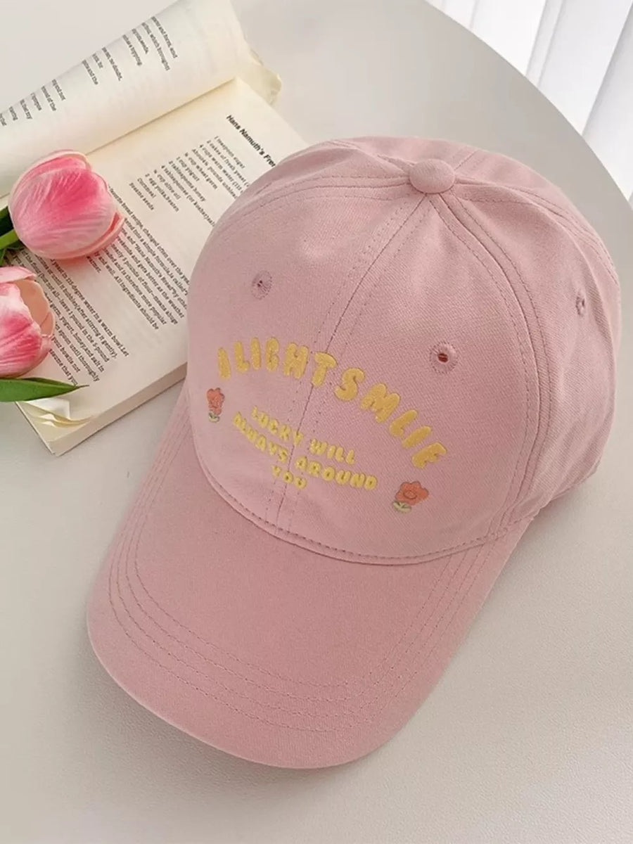 Pink baseball cap with yellow embroidered text and floral details