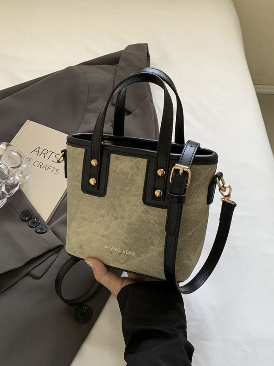 Mini chest bag in brown canvas with black leather trim and gold hardware.