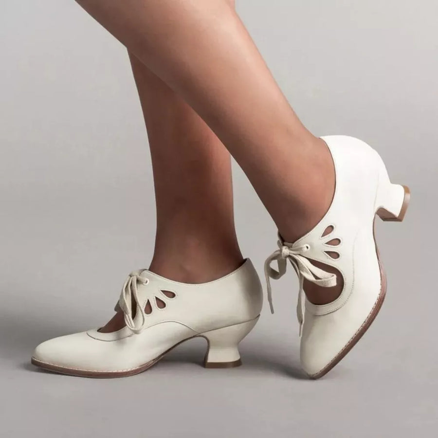 White leather lace-up heels with cut-out details and a flared heel.