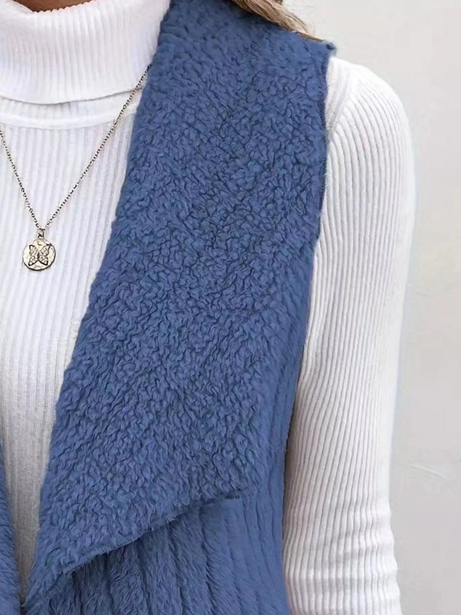 Blue open front fleece vest with a textured finish, layered over a white ribbed turtleneck.