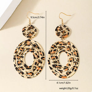 Bold dangle earrings in 18K gold with leopard print pattern and oval cutouts.