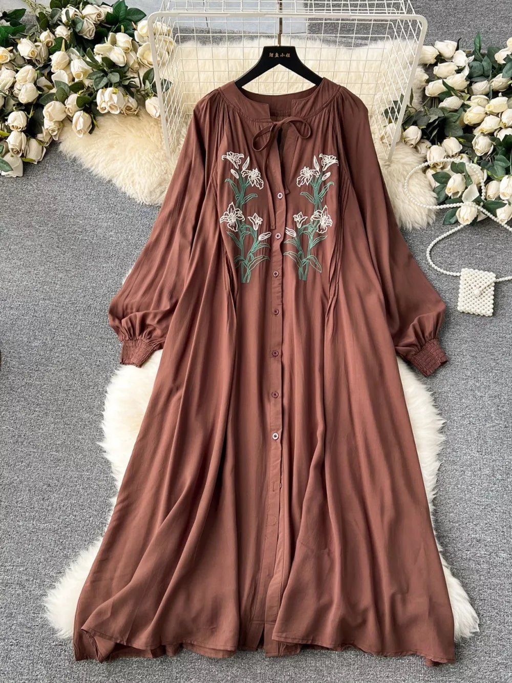Brown cotton maxi dress with embroidered floral detail and tie neck.