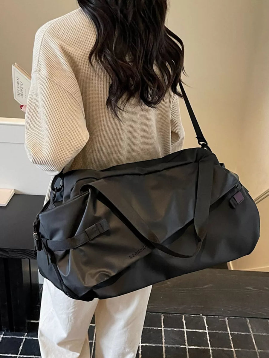 Black Oxford cloth travel bag with adjustable strap and buckle details.