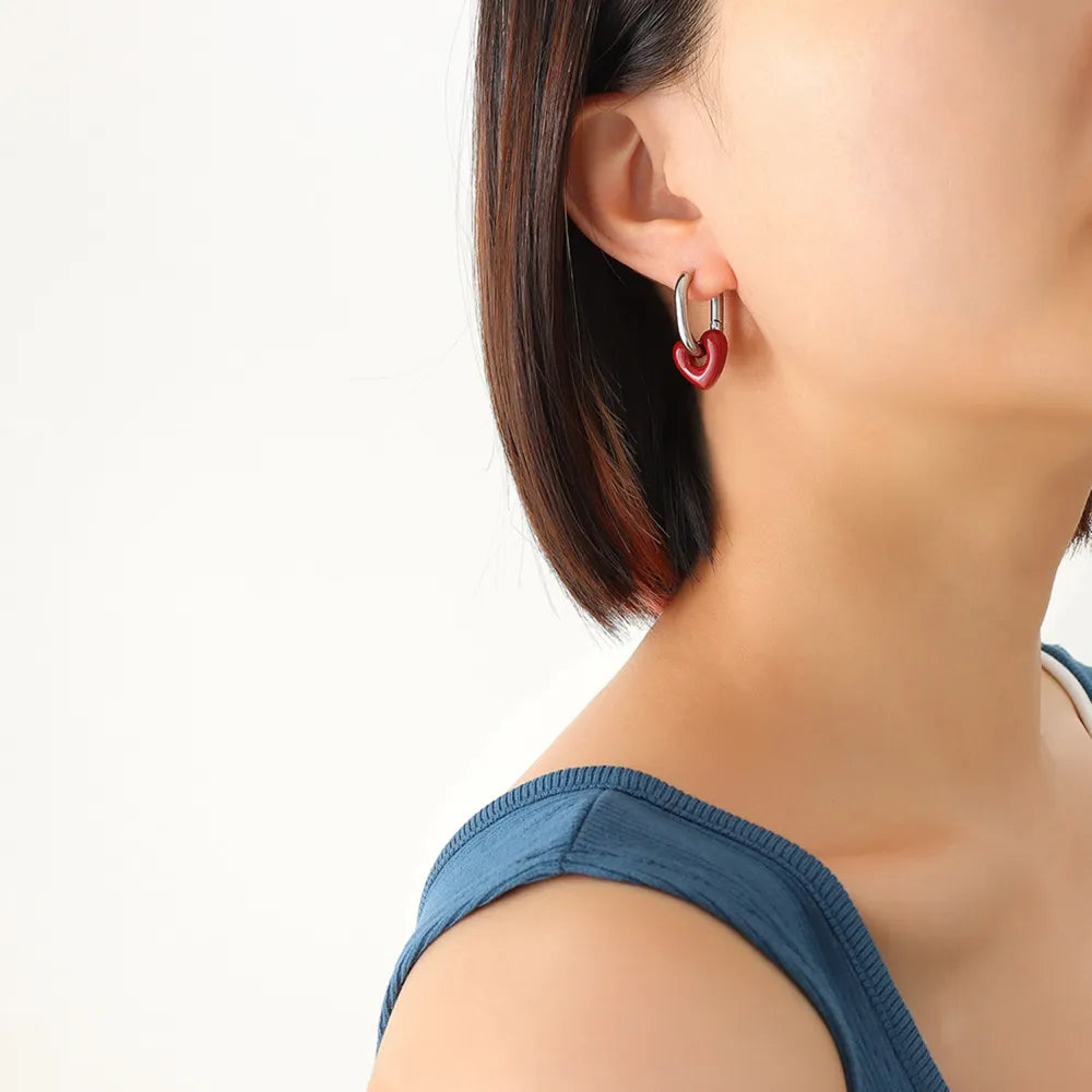Crimson heart enamel hoop earrings with silver hardware.