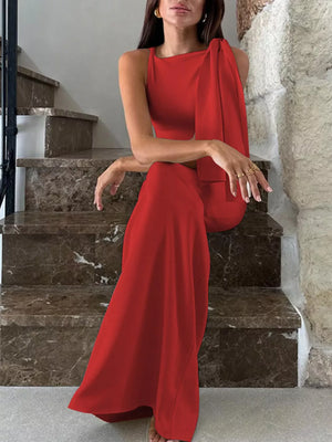 Red asymmetrical draped maxi dress with a sleeveless, high neckline and flowing skirt.