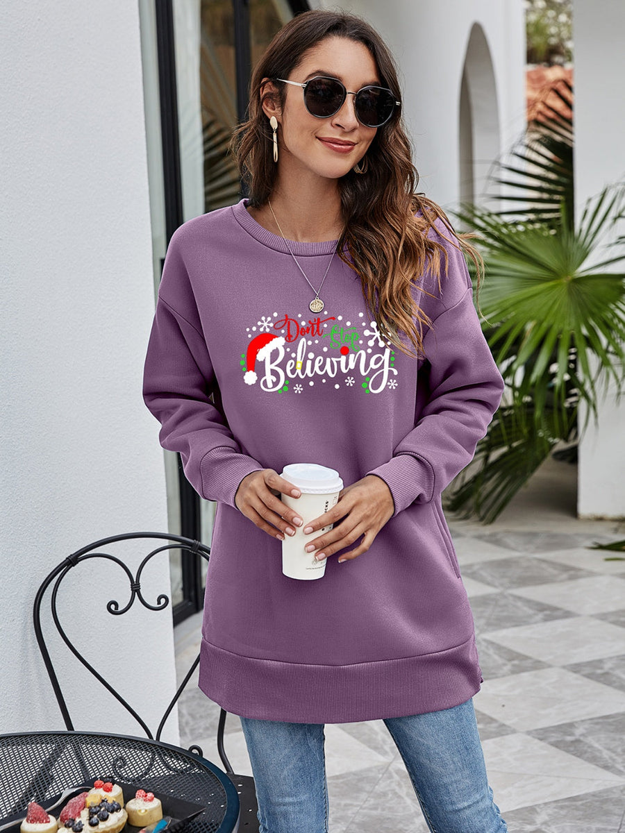 Purple graphic tunic sweatshirt with "Don't Stop Believing" holiday print, crew neck, long sleeves, and side pockets.