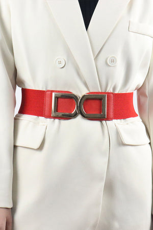 Red elastic belt with double gold buckle detail worn over a white blazer